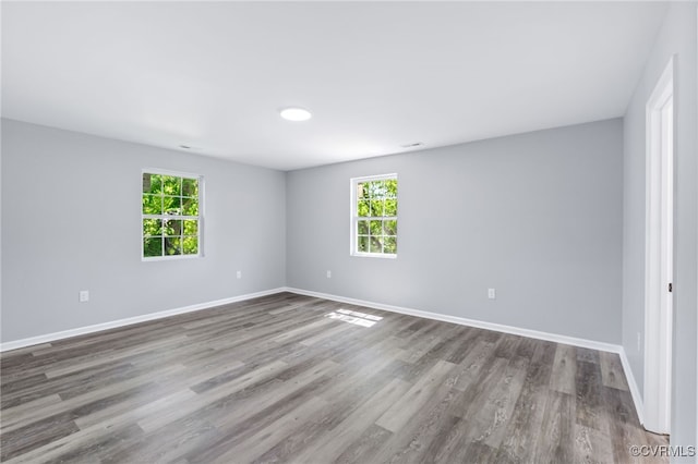 empty room with baseboards, a healthy amount of sunlight, and wood finished floors