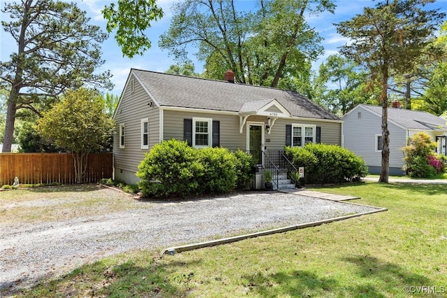 view of front of house with fence, a chimney, and a front lawn