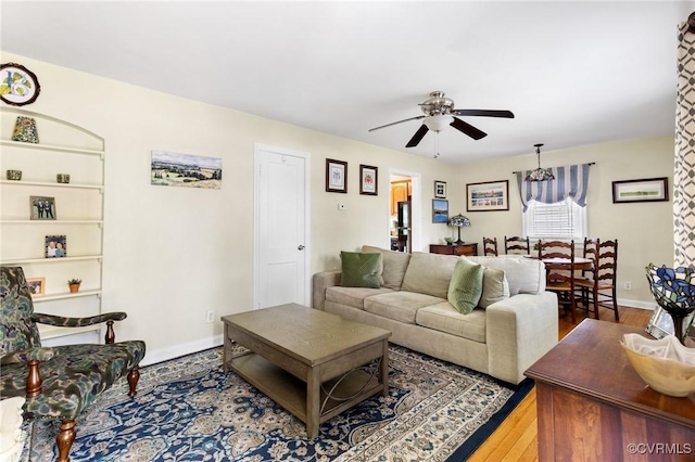 living room featuring baseboards, ceiling fan, and wood finished floors