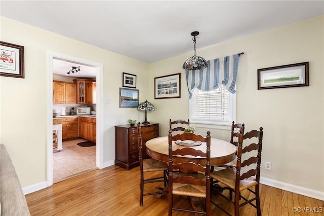 dining area featuring baseboards and light wood-type flooring