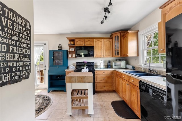 kitchen featuring light countertops, light tile patterned floors, a sink, and black appliances