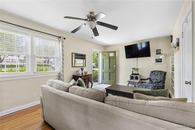 living area with baseboards, ceiling fan, and wood finished floors