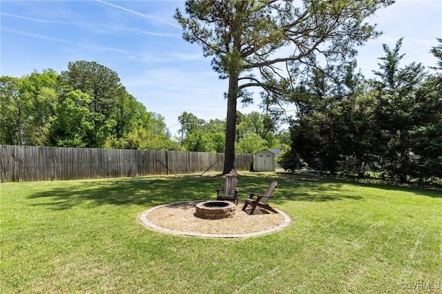 view of yard featuring a fenced backyard, a fire pit, a storage shed, and an outbuilding