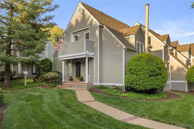 view of front of property with a front lawn, roof with shingles, and a balcony
