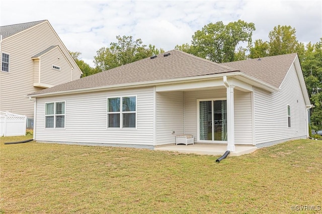 rear view of property featuring a lawn, a patio, and a shingled roof