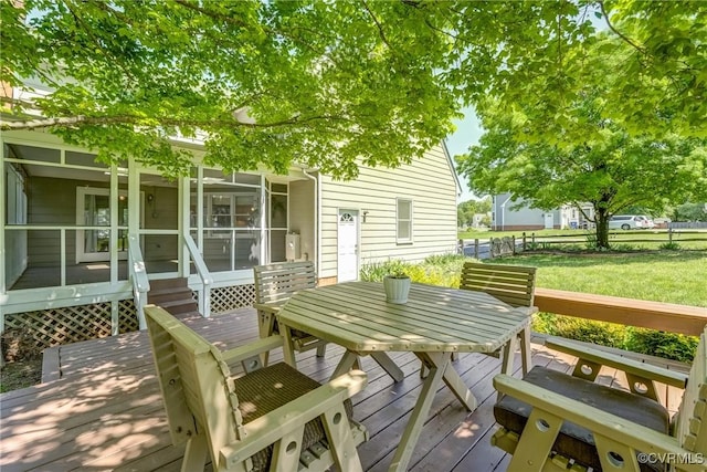 deck featuring a sunroom, fence, a yard, and outdoor dining space