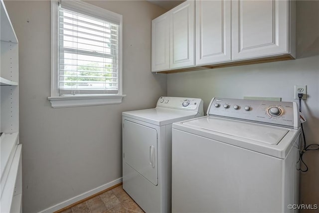 clothes washing area with baseboards, cabinet space, and washer and dryer