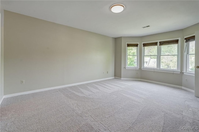 empty room with baseboards, visible vents, a wealth of natural light, and light colored carpet
