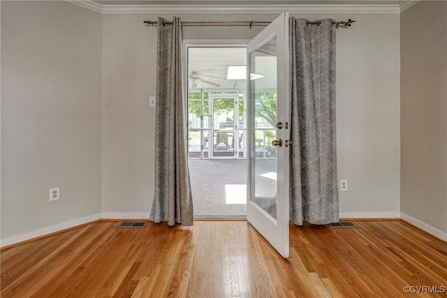 doorway to outside with light wood-style floors, baseboards, ornamental molding, and visible vents