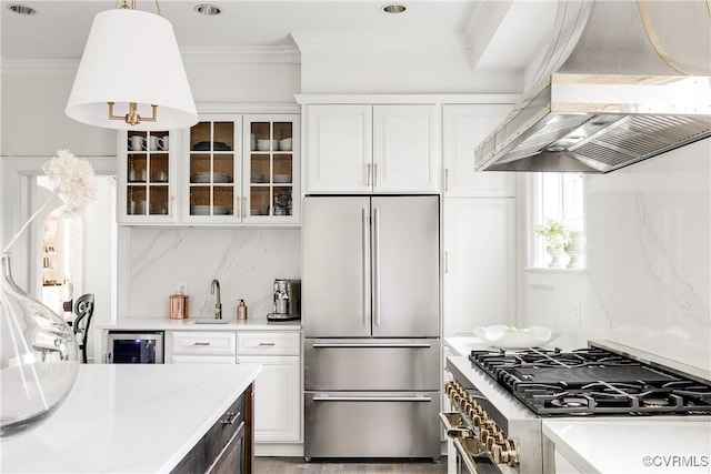7 River Rd, Richmond, VA 23226 - kitchen with appliances with stainless steel finishes, wall chimney range hood, light countertops, beverage cooler, and glass insert cabinets