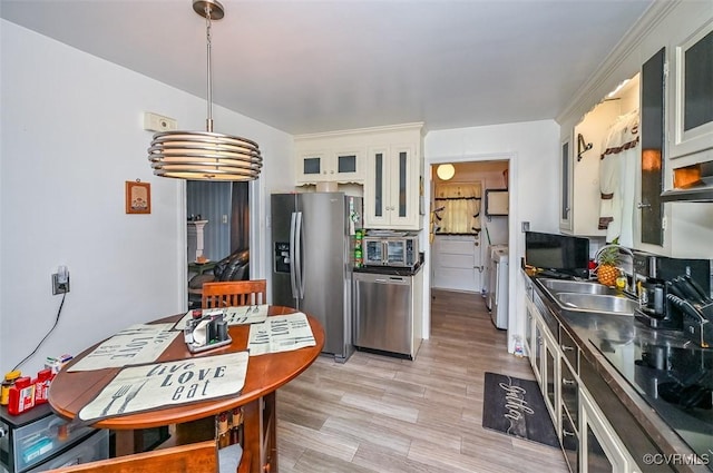 kitchen with a sink, appliances with stainless steel finishes, white cabinetry, and glass insert cabinets