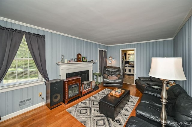 living room featuring crown molding, a fireplace, wood finished floors, and visible vents