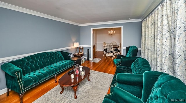 living room with crown molding, baseboards, wood finished floors, and a chandelier