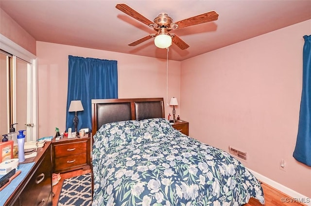 bedroom with ceiling fan, baseboards, visible vents, and wood finished floors