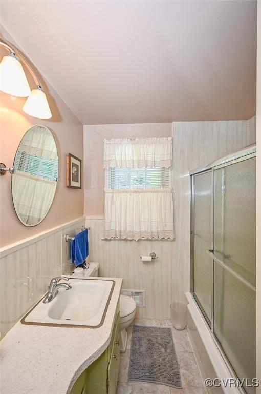 bathroom featuring tile patterned flooring, vanity, toilet, vaulted ceiling, and visible vents
