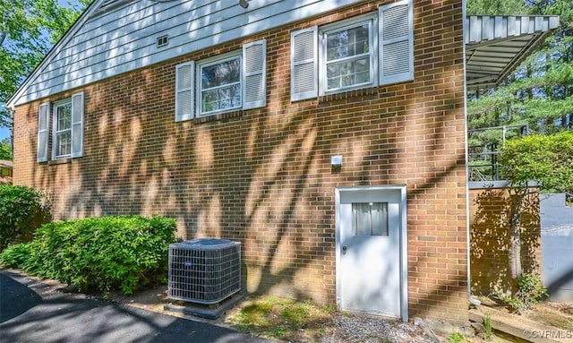 view of side of home featuring brick siding and central AC unit