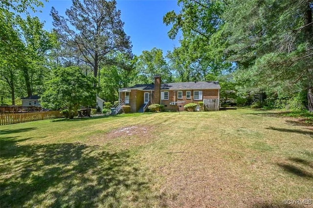 exterior space with a lawn, fence, and a chimney