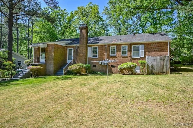 back of house with brick siding, crawl space, a lawn, and a chimney