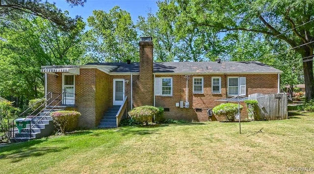 back of property featuring brick siding, crawl space, a yard, and a chimney