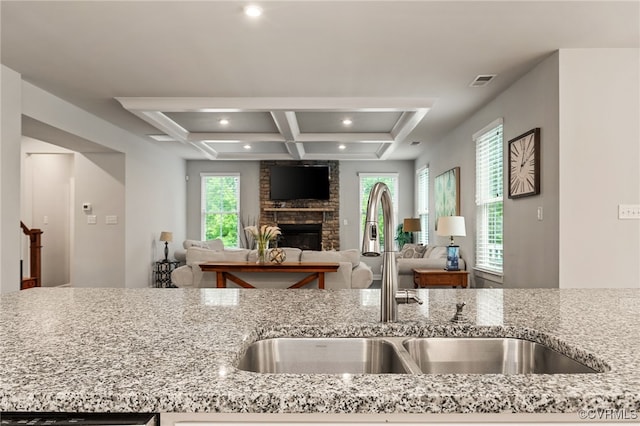 kitchen featuring visible vents, a fireplace, light stone countertops, recessed lighting, and a sink