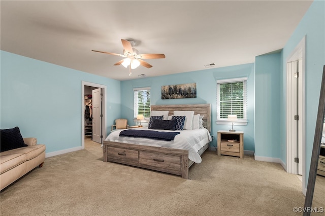 bedroom with a walk in closet, ceiling fan, visible vents, baseboards, and carpet