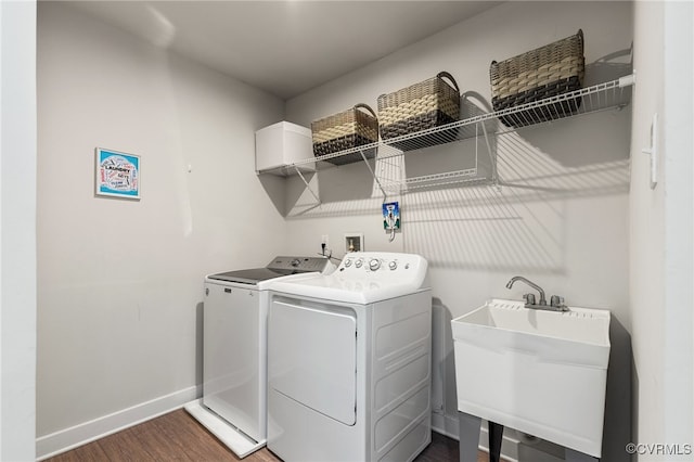 washroom featuring laundry area, baseboards, dark wood-style floors, separate washer and dryer, and a sink