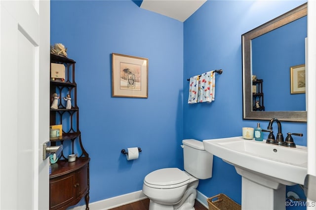 half bath featuring baseboards, a sink, wood finished floors, and toilet