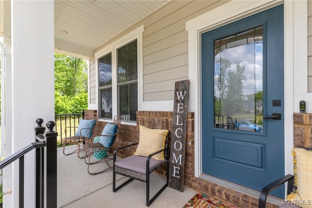 view of exterior entry featuring a porch and brick siding