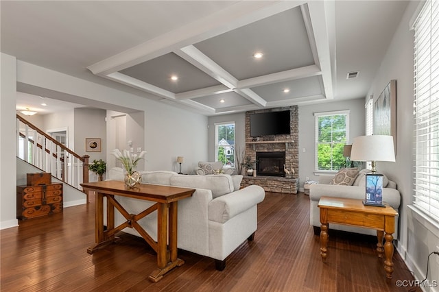 living area with visible vents, stairs, dark wood-style flooring, and a stone fireplace