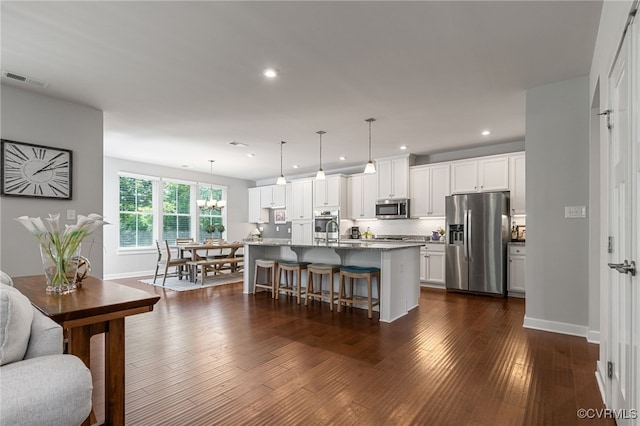 kitchen with a breakfast bar area, visible vents, a center island with sink, white cabinets, and stainless steel appliances