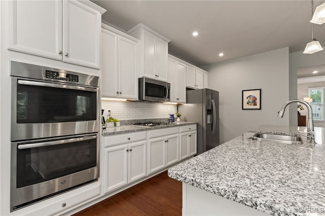 kitchen with tasteful backsplash, a sink, white cabinets, stainless steel appliances, and recessed lighting