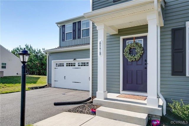doorway to property featuring a garage, board and batten siding, driveway, and central AC