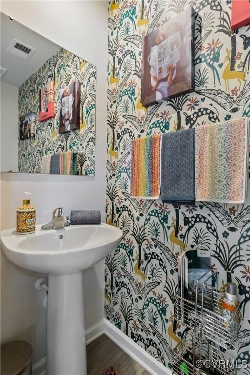 bathroom featuring baseboards, a sink, wood finished floors, and visible vents