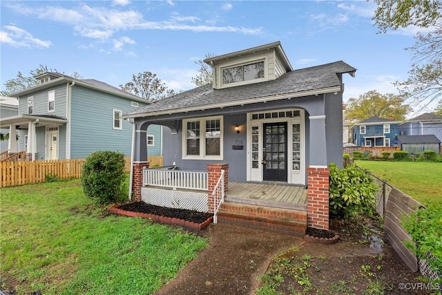 bungalow-style house featuring a porch, a front lawn, fence, and stucco siding