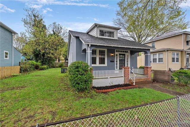 bungalow-style house featuring a porch, roof with shingles, fence, and a front yard
