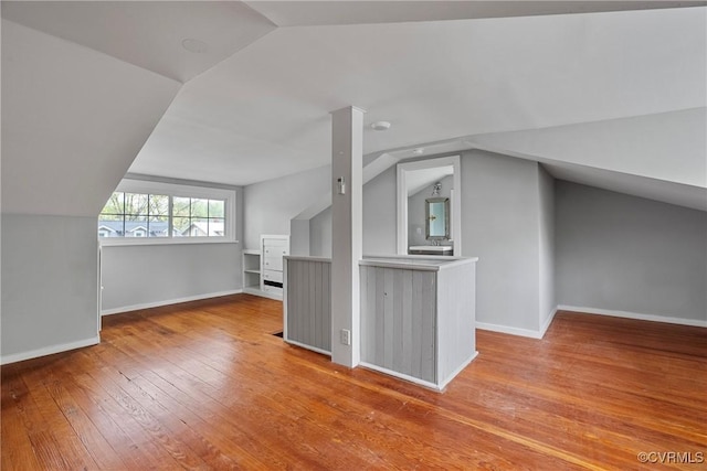 bonus room featuring baseboards, vaulted ceiling, and hardwood / wood-style flooring