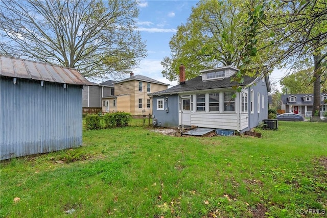 back of property with a chimney, a storage shed, central AC unit, an outdoor structure, and a yard