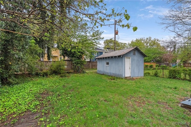 view of yard featuring a storage unit, a fenced backyard, and an outbuilding