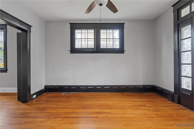 spare room with plenty of natural light, light wood-style flooring, ceiling fan, and baseboards