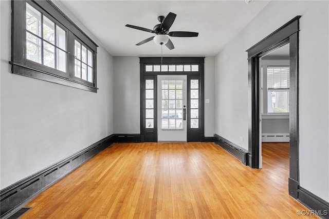 foyer featuring visible vents, light wood-style floors, baseboards, baseboard heating, and a ceiling fan
