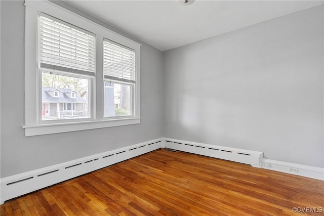 spare room featuring a baseboard radiator and wood finished floors