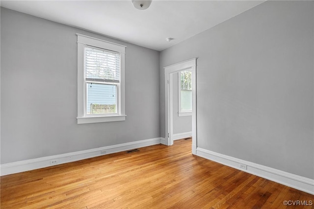 spare room with baseboards, light wood-style flooring, and visible vents