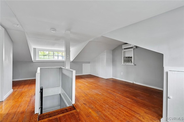 bonus room with baseboards, vaulted ceiling, hardwood / wood-style floors, and a wall mounted air conditioner