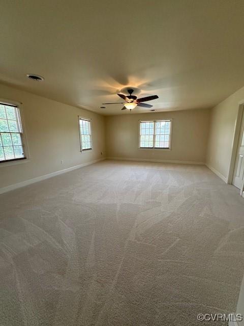 unfurnished room with baseboards, a ceiling fan, and a wealth of natural light
