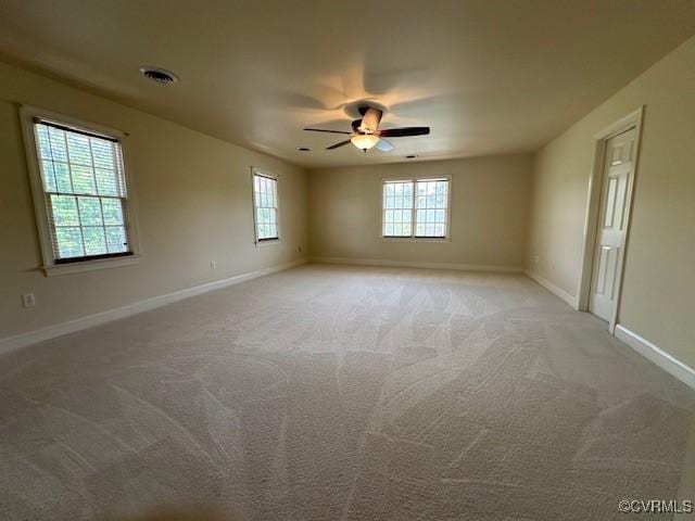 unfurnished room with baseboards, ceiling fan, light colored carpet, and visible vents