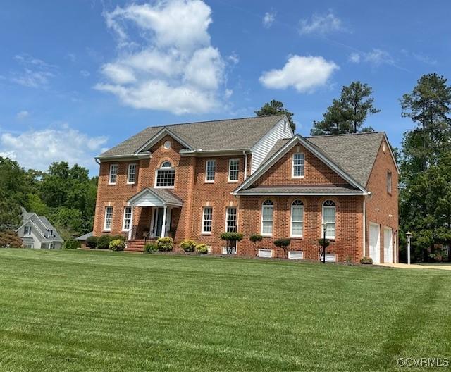view of front of property with an attached garage, a front yard, brick siding, and covered porch