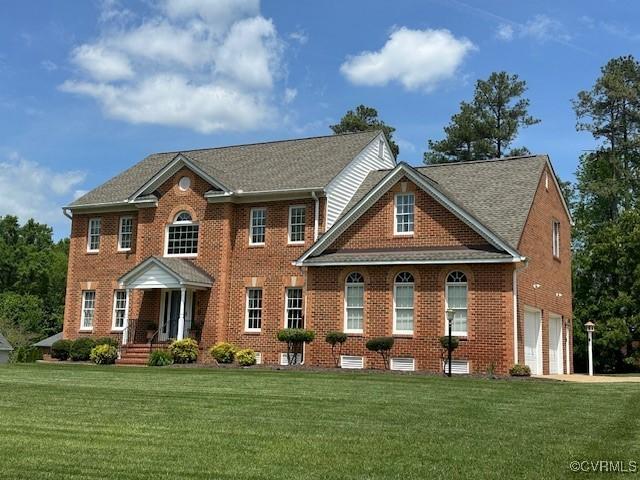 view of front facade with brick siding, a front lawn, an attached garage, and concrete driveway