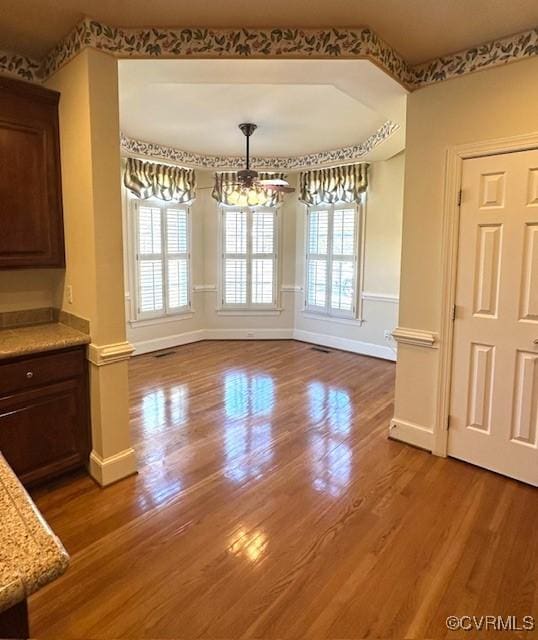 unfurnished dining area with baseboards and wood finished floors