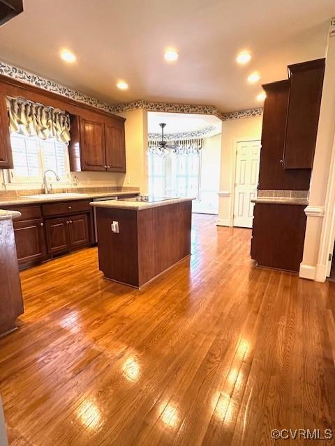 kitchen with light countertops, a center island, light wood-type flooring, and a sink