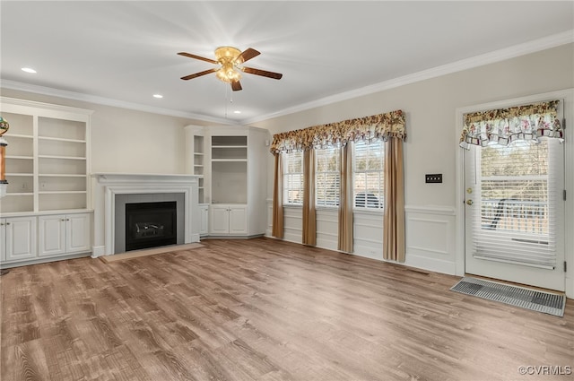 unfurnished living room featuring crown molding, ceiling fan, light wood finished floors, and a fireplace with flush hearth
